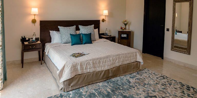 Bedroom with a double bed, bedside tables, lamps, and a blue rug at Karma Chalets.