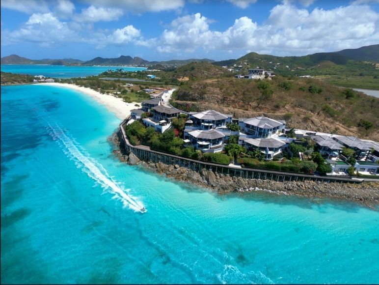 Aerial view of Tamarind Hills Resort and Villas in Antigua, perched on a scenic peninsula with turquoise waters, sandy beaches, and lush green hills.