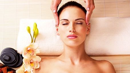 Woman relaxing during a spa treatment with flower petals and oils.
