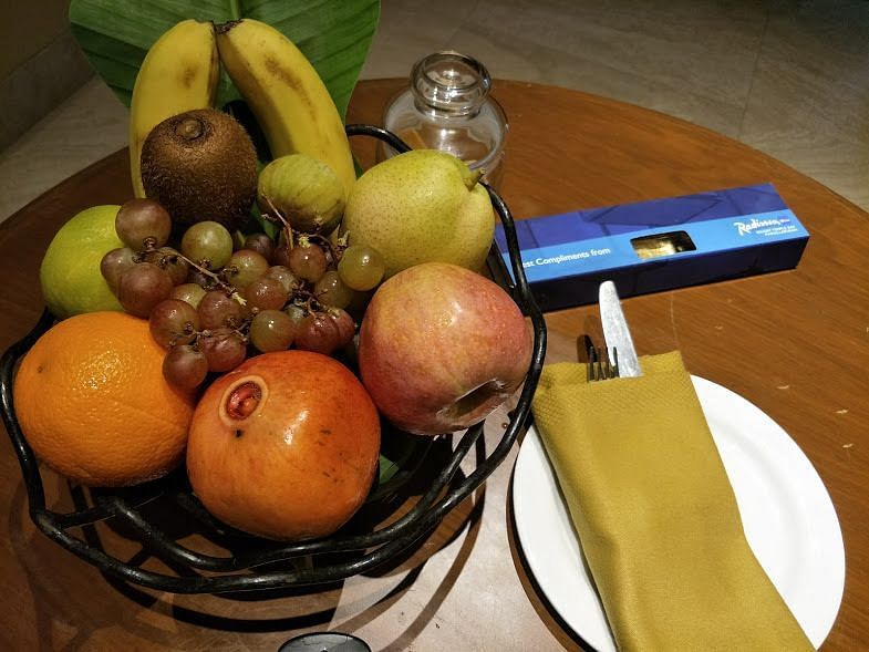 A fruit basket placed on a table with cutlery.