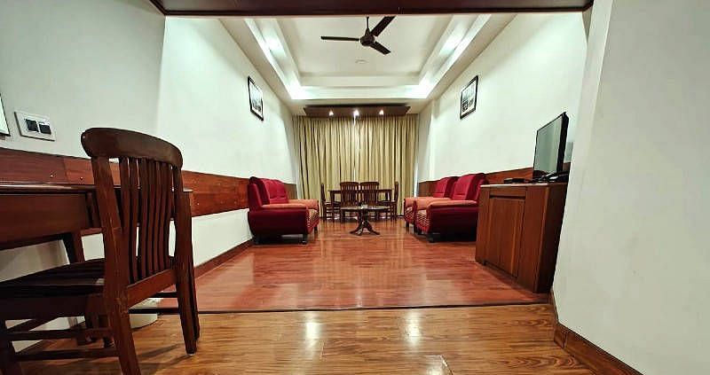 The living room of the Suite featuring a shiny wooden flooring along with red coloured couch set in the end - Hotel Gold, Panipat