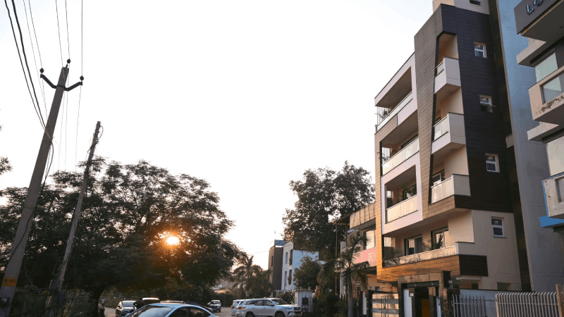 Street view featuring multiple storey buildings, parked vehicles, and overhead power lines at dusk.