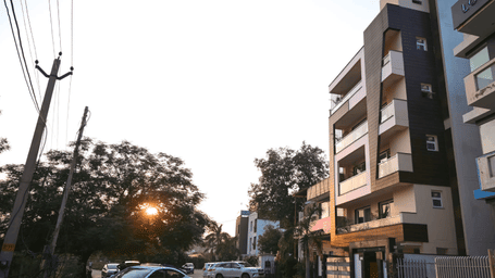 Street view featuring multiple storey buildings, parked vehicles, and overhead power lines at dusk.
