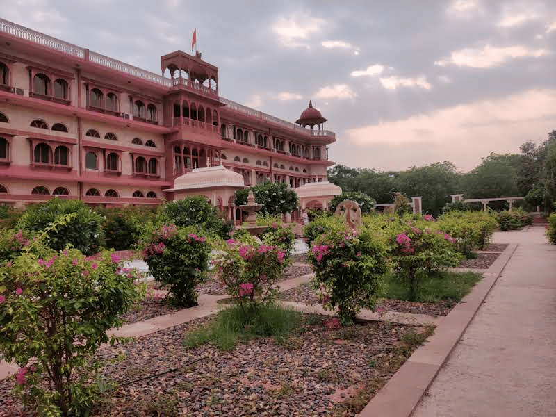 The grand facade of the Umaid Palace resort stands elegantly behind a beautifully manicured heritage garden.