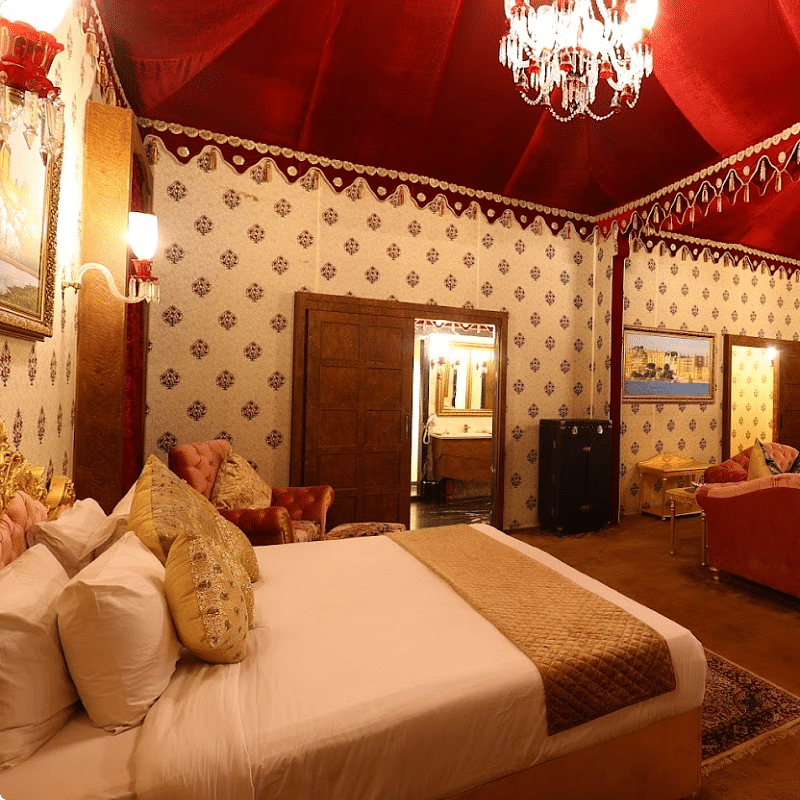 Image of a room with a bed and chandeliers hanging from the ceiling at Rajasthali Resort & Spa Jaipur.