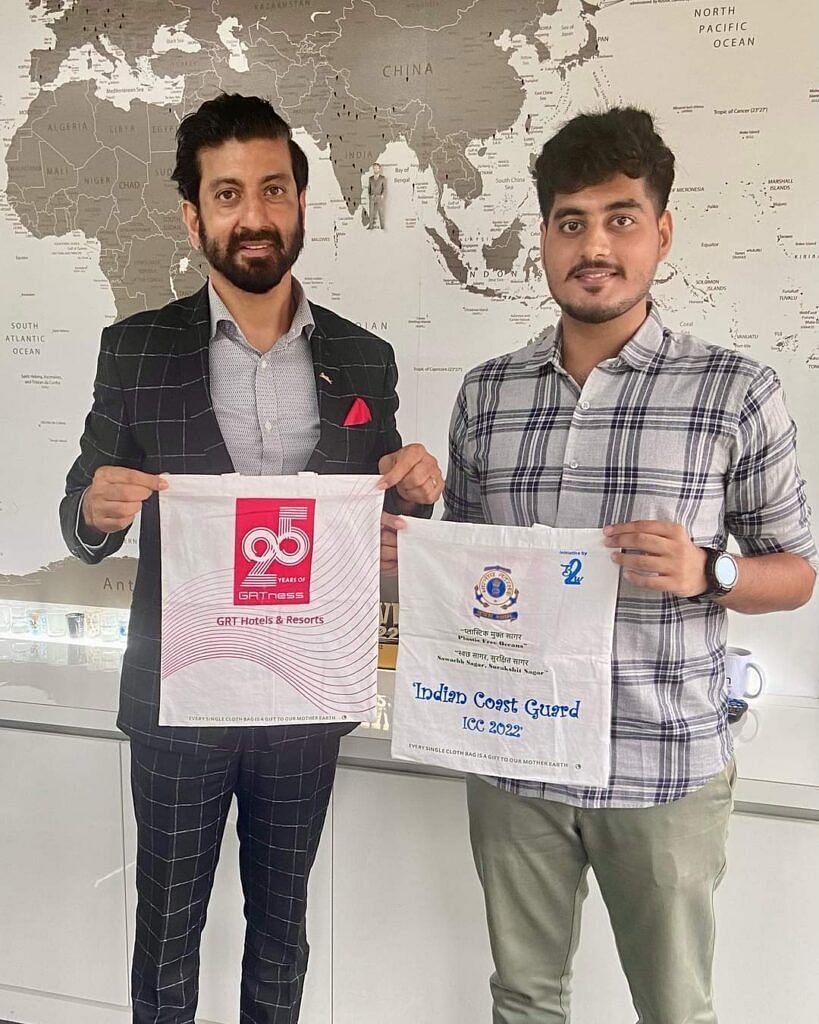 Two men showing GRT Hotel and Indian Coast Guard ICC 2022 banners in their hands.