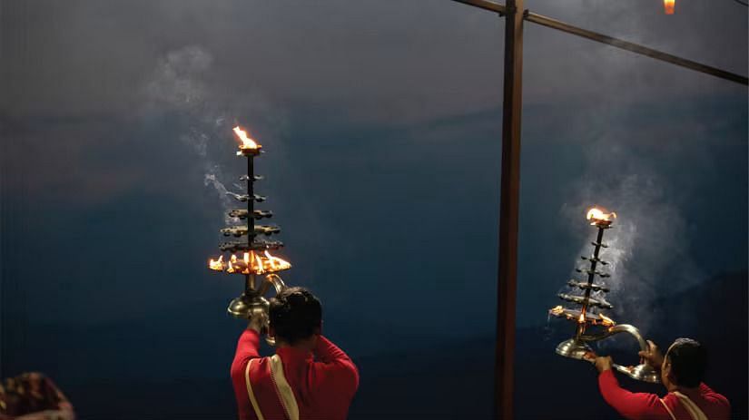 A person holding a traditional Indian lamp with multiple flames, creating a beautiful pattern of light and smoke.