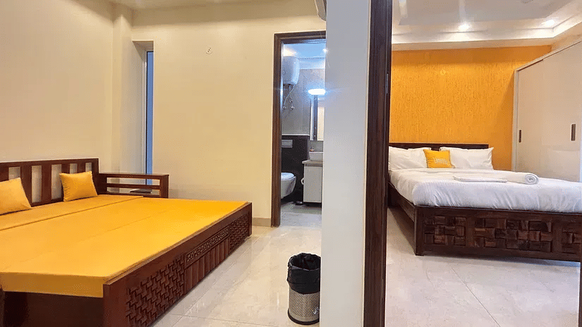 Open layout bedroom and seating area at Lime Tree 1BHK Serviced Apartment Near Medanta Hospital Gurgaon with cushioned sofa air conditioning and functional design for short and long term stay