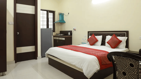 Bedroom of Lime Tree Hotels & Service Apartment Private Limited featuring a maroon striped bedspread and a patterned headboard.