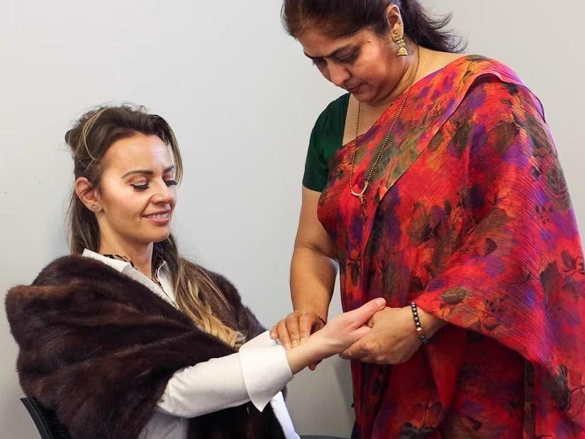  An Ayurvedic practitioner examining a woman's pulse during a consultation.