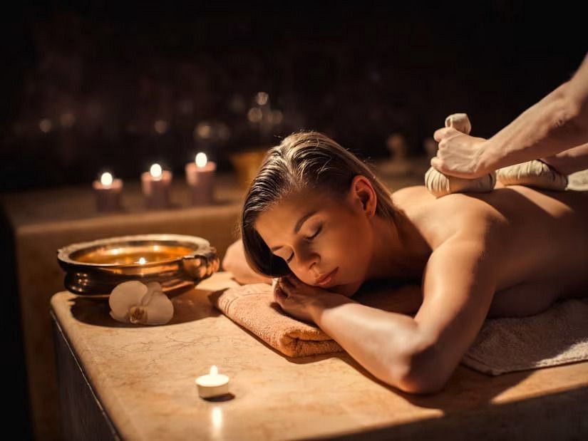 A woman receiving a therapeutic massage with herbal pouches at YO1, Catskills, New York, highlighting holistic wellness treatments.