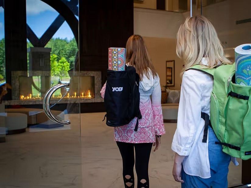Two women enterting a building with yoga mats in their bag