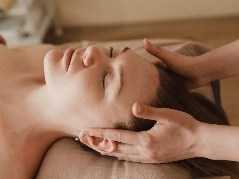 a woman lying on her back and getting a massage on her temples