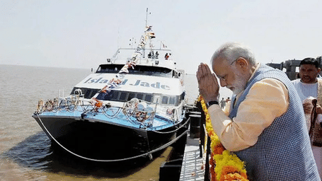 A man in a white suit with his hands together next to a large boat.