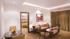 A living room of the Superior Suite at The Retreat Hotel and Convention Centre Madh Island Mumbai, with a couch, tables and chairs.