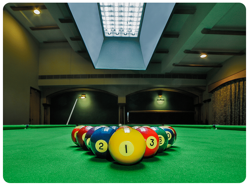 Indoor snooker table with colorful balls arranged for play.