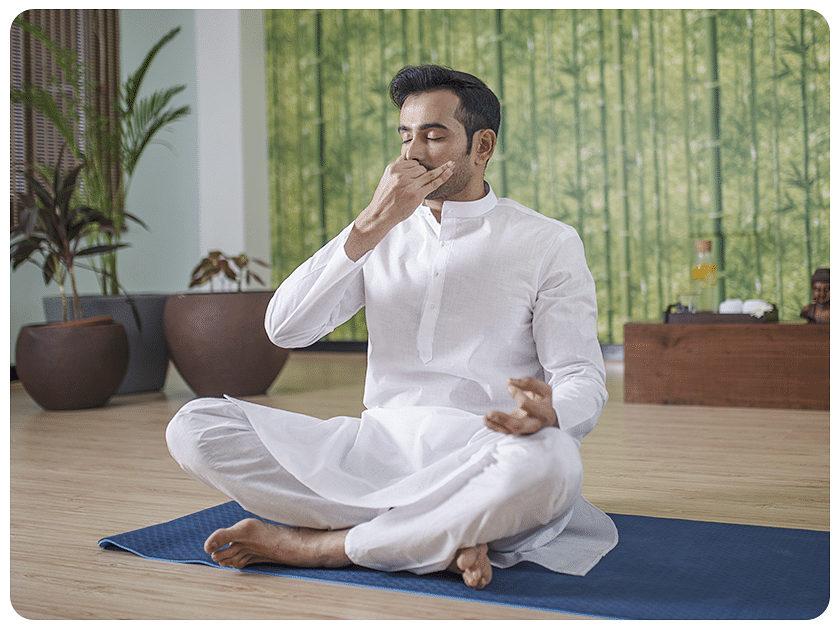 Man in white clothing practicing yoga indoors.