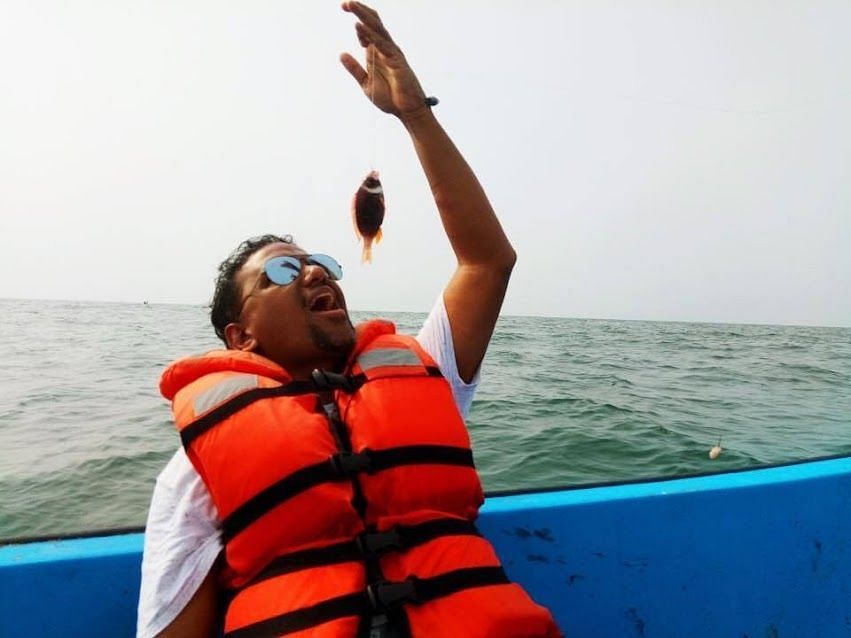 An image of a person posing with a fish hanging from fish thread.