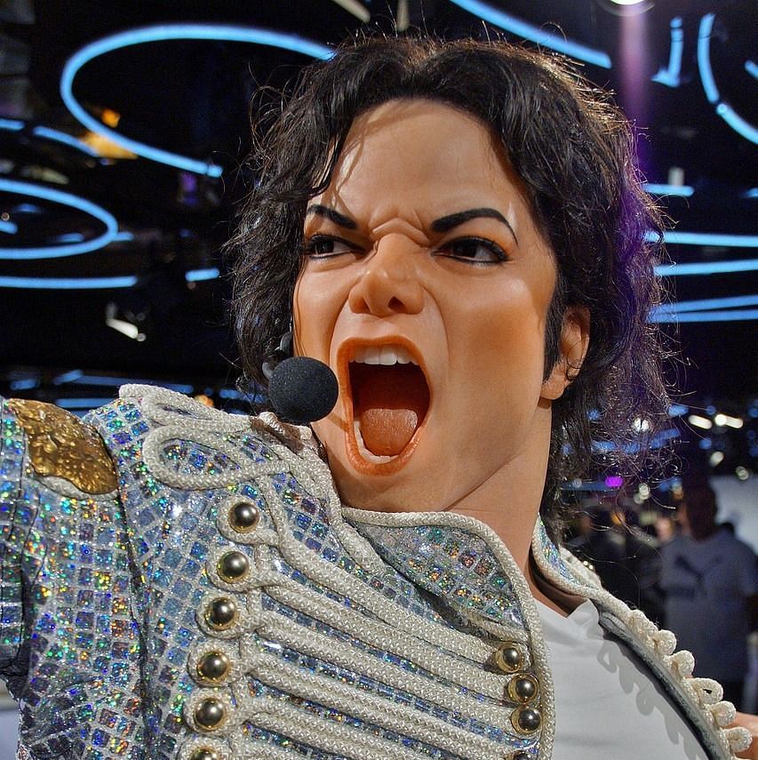 Lifelike wax statue of a performer with an expressive pose in a museum setting.
