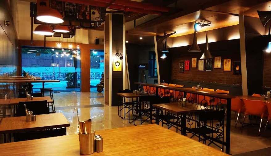 View of Mumbai Masala Restaurant with contemporary seating, warm decor, and large window - Max Hotel Prayagraj.