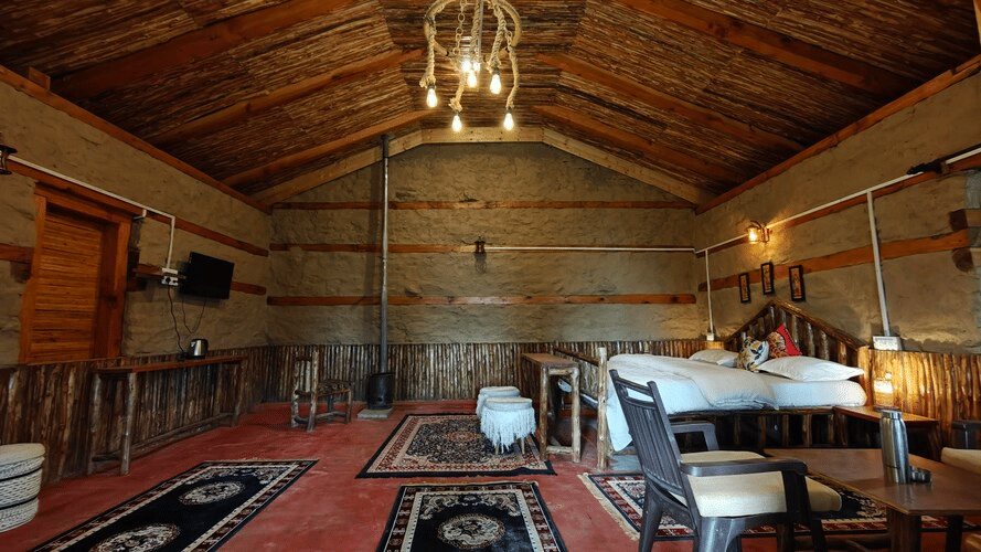 Full view of the Hamta Peak Cottage featuring earthy interiors decorated with beautiful, intricately-patterned rugs at Amara Upepo - The Sky Village, Manali.