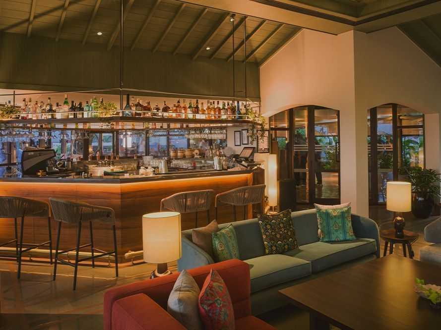 A full-view shot of the bar at Athiva Hotels with warm ambient lighting and plush seating arrangements.