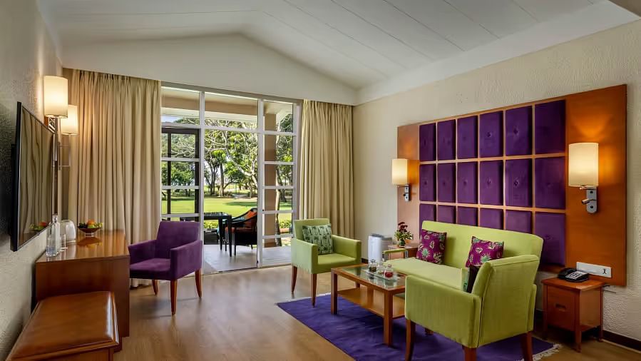 the living room inside Garden Villa with sofas, lamps and door to balcony - Caravela Beach Resort Goa