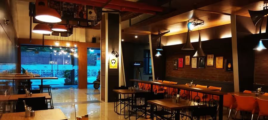 View of Mumbai Masala Restaurant with contemporary seating, warm decor, and large window - Max Hotel Prayagraj.