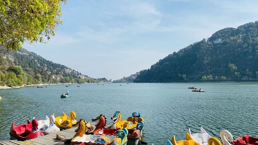 A beautiful shot of a water body with green hills and some boats on the shot.