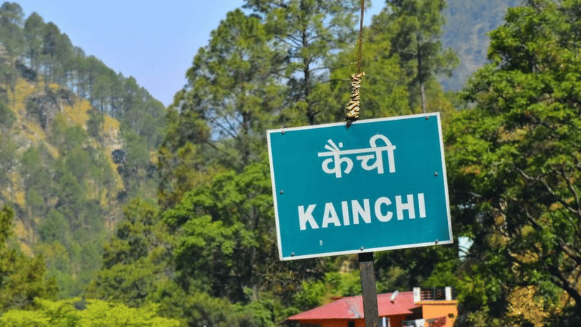 A board reading Kainchi, with lush greenery on the background.