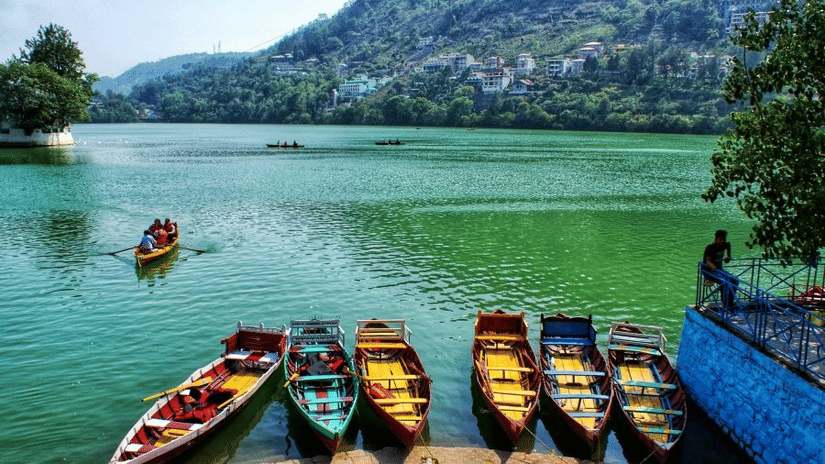 A shot of a water body with green hills and some boats on the shot.