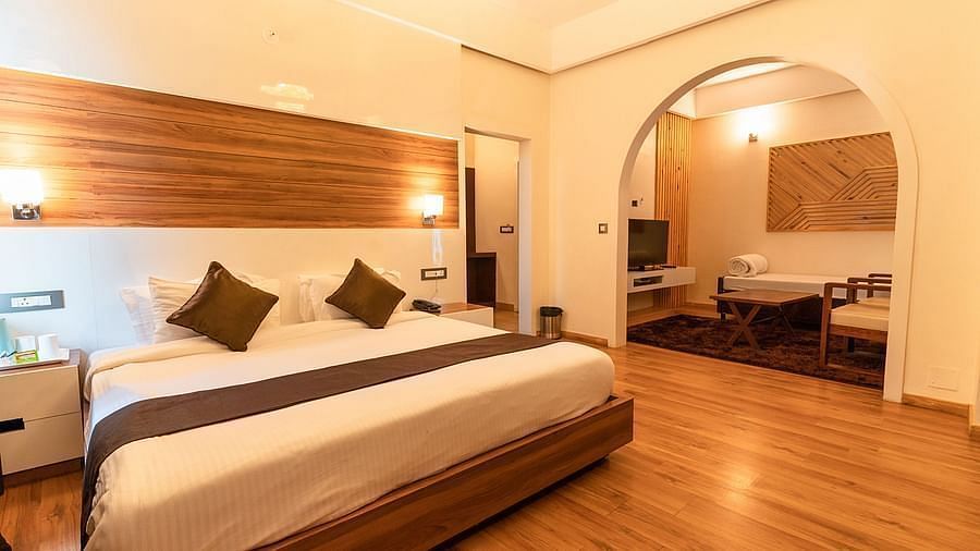 A bedroom with a white bed, a rug, and warm lighting, interior setting - Clarks Exotica Resort, Near Mukhteshwar.