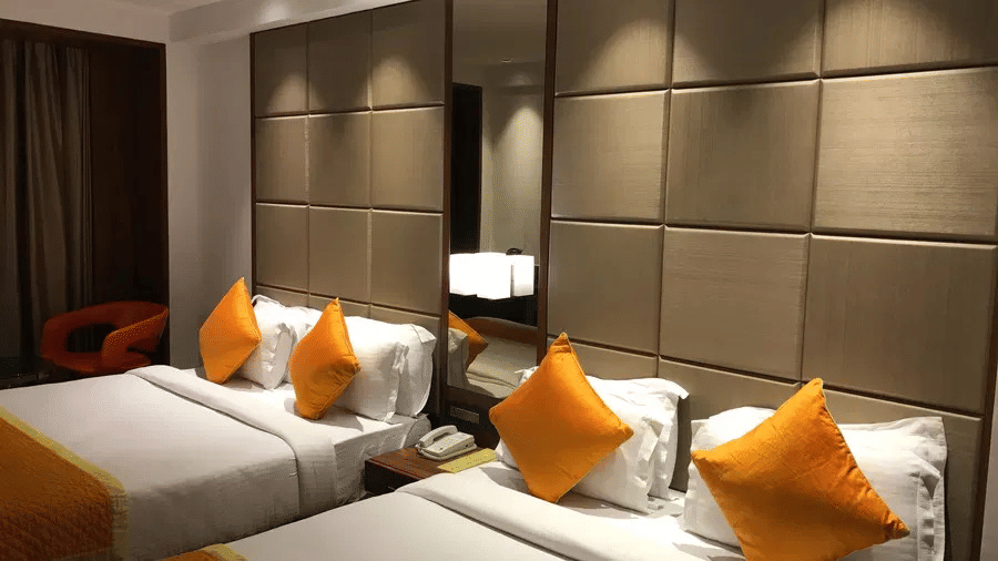 A room with double beds, pillows, sheets, and switch board.