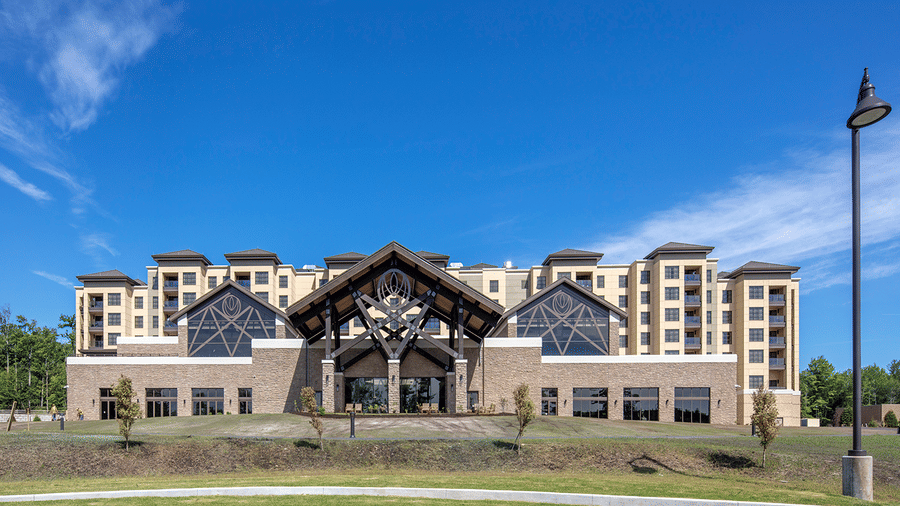 Exterior view of YO1 Wellness Center in New York, featuring its grand timber-framed entrance, landscaped lawns, and expansive resort-style façade set beneath a clear blue sky.