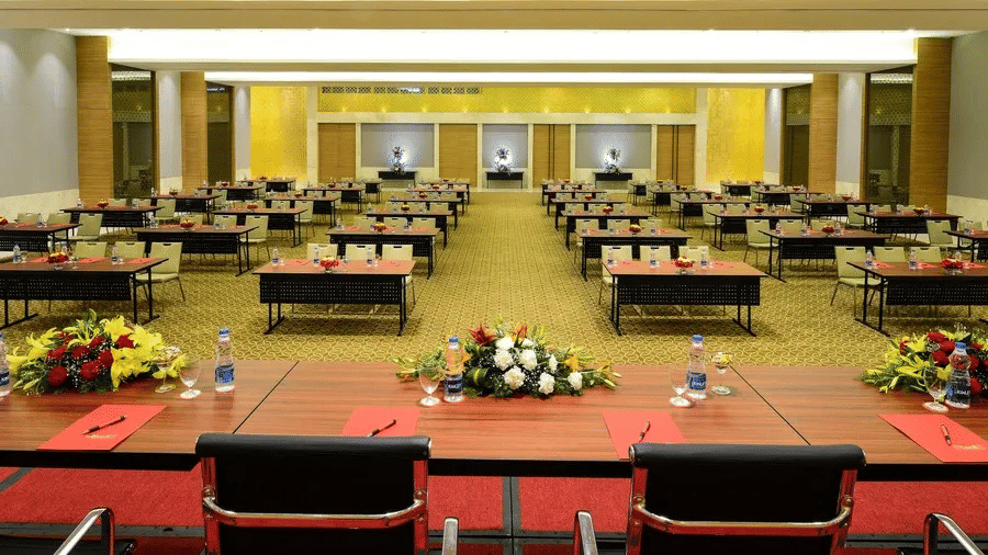 Conference hall at Daspalla Hotels arranged in a classroom style setup with neatly placed tables, chairs, floral centrepieces, and presentation seating for corporate meetings and events.