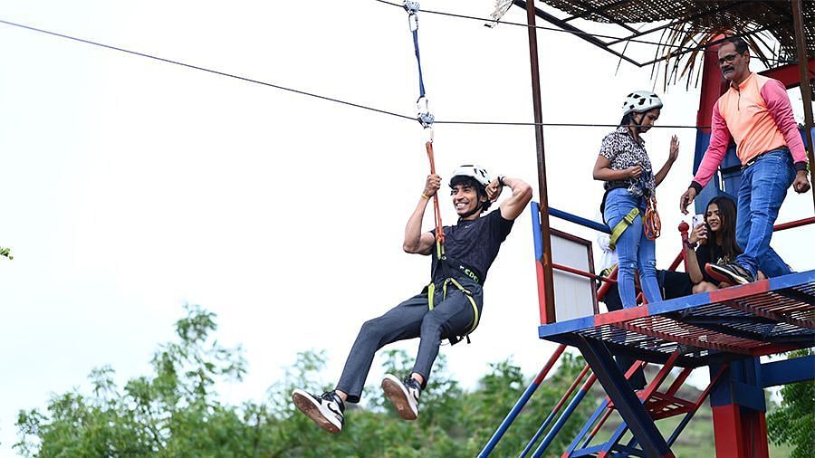 An overview of a person performing a zip lining activity with people on top looking - Diamond Parks, Pune.