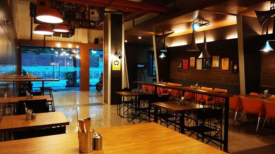 View of Mumbai Masala Restaurant with contemporary seating, warm decor, and large window - Max Hotel Prayagraj.