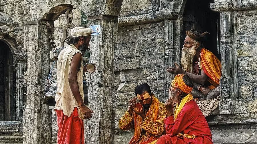  A group of Hindu ascetics (sadhus) dressed in traditional attire, situated outside an ancient temple.