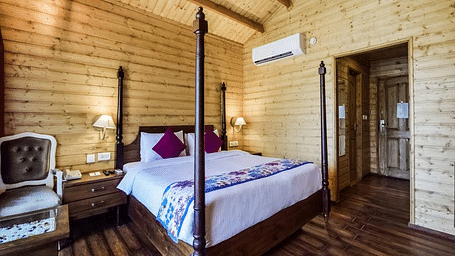 A cosy room with wooden walls, a four-poster bed, and a vintage chair. - Bamboo Saa Resort & Spa, Udaipur