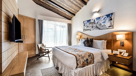 A modern hotel room with a plush bed, a TV, and a wooden accent wall. - Bamboo Saa Resort & Spa, Udaipur
