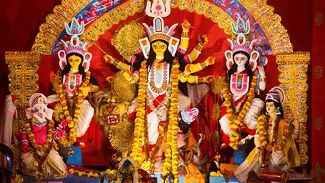 A large and vibrant Durga Puja idol, showing the goddess Durga with ten arms slaying a demon. She is surrounded by her children: Lakshmi, Saraswati, Ganesha, and Kartikeya.