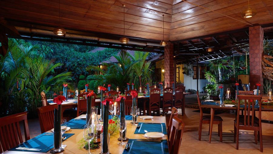 Restaurant interior with wooden ceiling and large windows showing lush greenery - BluSalzz Collection - Tranquil Resort, Wayanad