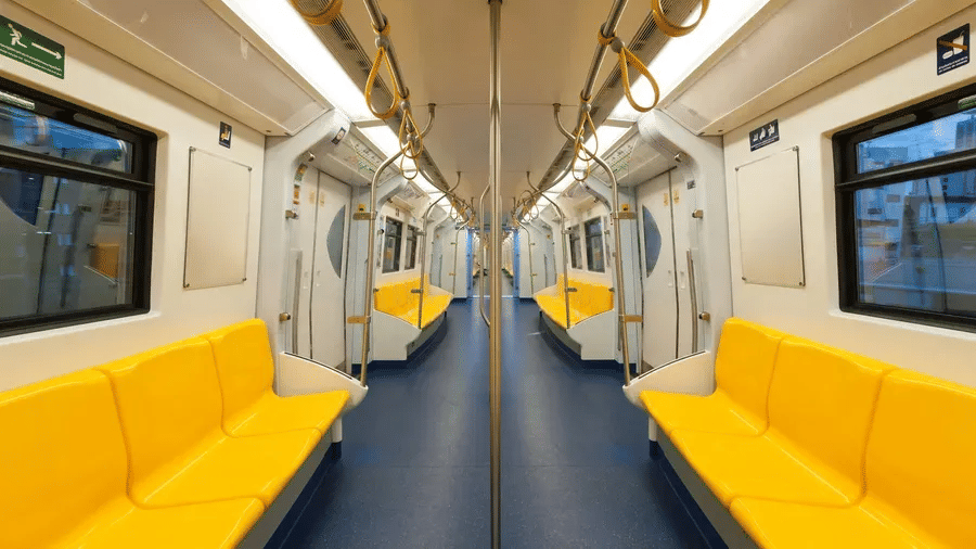 Empty metro carriage with rows of yellow seats and handrails