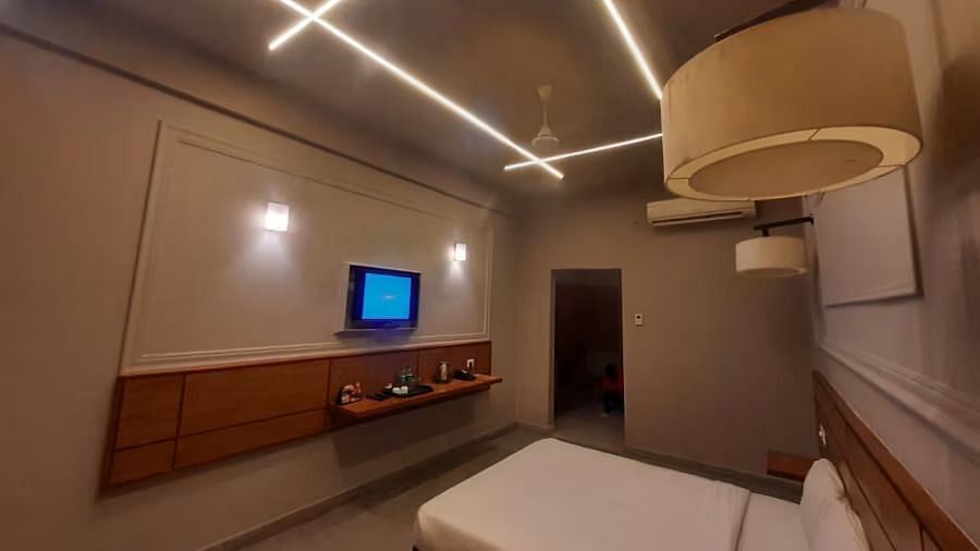 Side view of a room with a bed, TV mounted on the wall, and a lamp - Max Hotel Prayagraj.