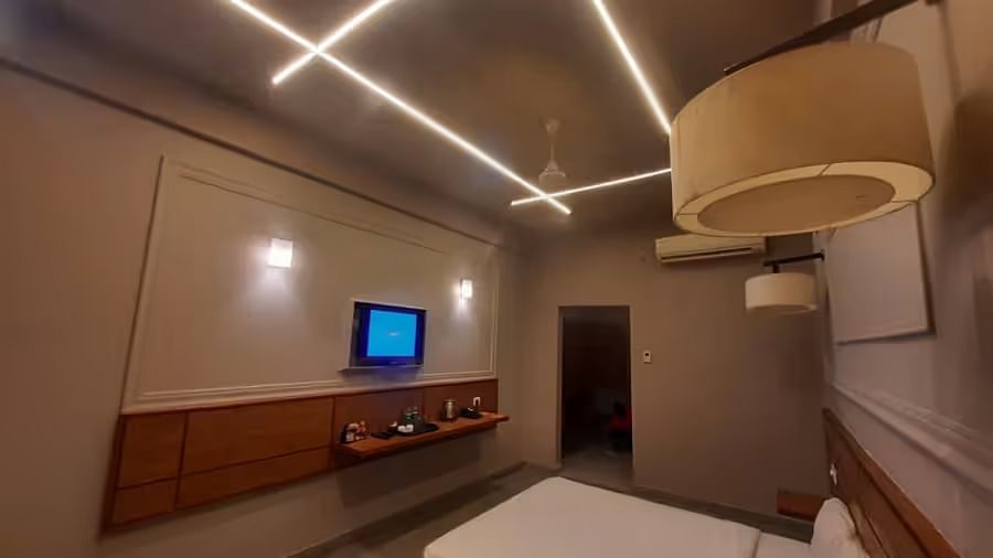 A sleek and modern hotel room featuring warm LED strip lighting, a TV, and a stylish bed- Max Hotel Prayagraj.