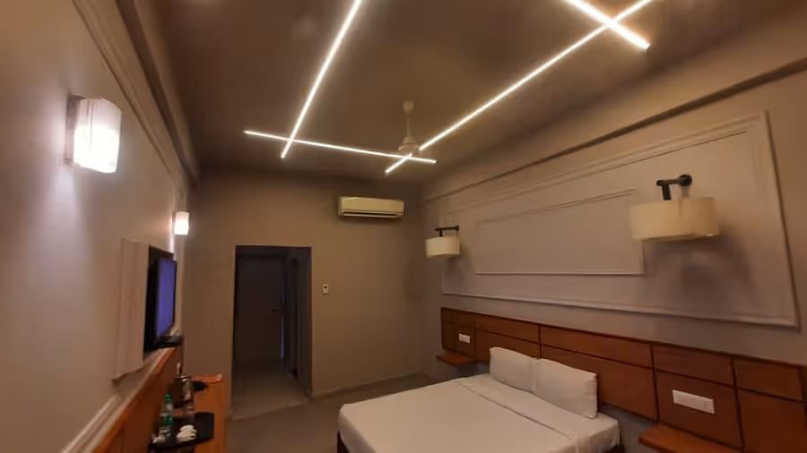 View of a stylish hotel room with a bed, tv mounted on the wall, and a lamp featuring a sleek design - Max Hotel Prayagraj.