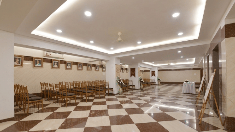 Empty event hall with a checkered floor, gradient ceiling lights, and chairs lined up along the side.