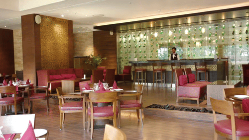 The interior of the best restaurant in Malad West with tables, chairs, and a bar area in the background of The Retreat Hotel & Convention Centre.