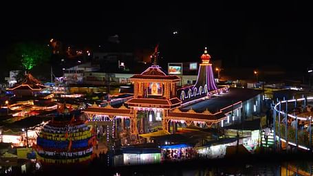 A beautifully illuminated temple complex at night, with surrounding structures lit up.
