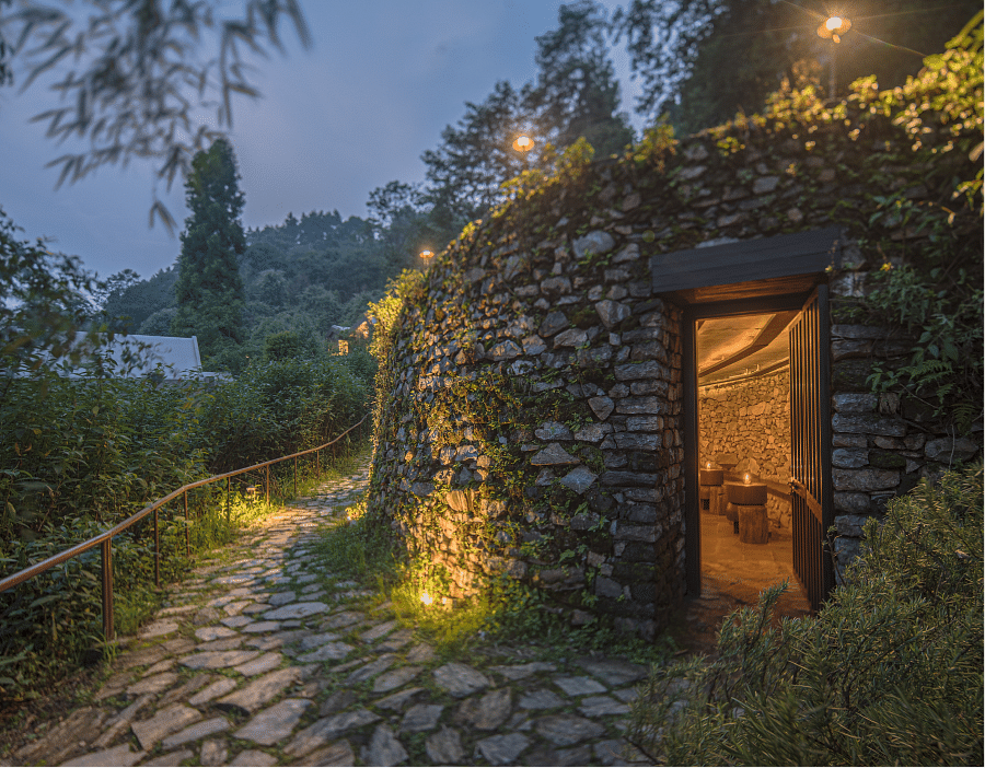 A small cottage with lights on and a pavement with grasses on each side | Kavya Resort and Spa, Nagarkot